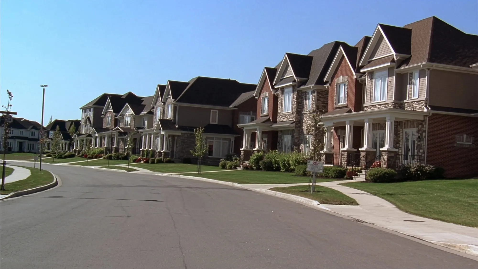 Illustrative photo of a newer Milton subdivision street of brick and stone homes with the escarpment on the horizon